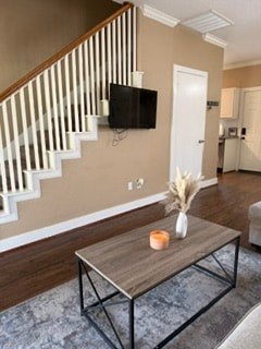A living room with a television, a coffee table, and a staircase.