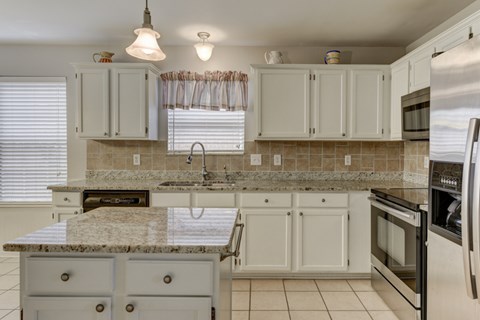 A kitchen with white cabinets and a granite countertop.
