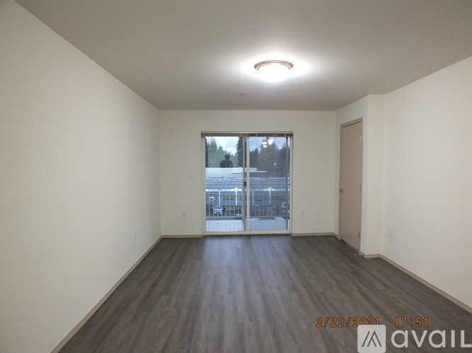 A room with wooden floors and a large window overlooking a parking lot.