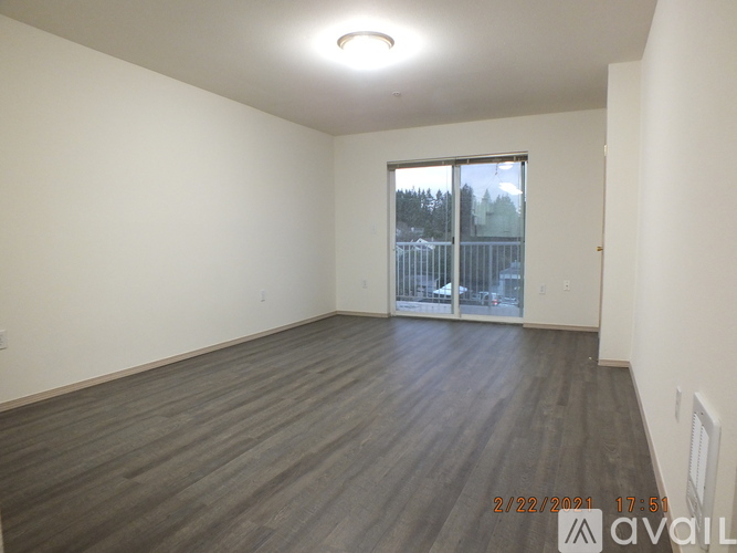 A room with wooden flooring and a sliding glass door leading outside.