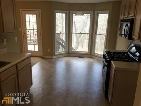 A kitchen with a black stove top oven and wooden cabinets.