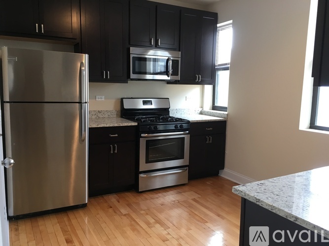 A kitchen with black cabinets and a stainless steel refrigerator.