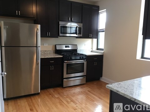 A kitchen with black cabinets and a stainless steel refrigerator.