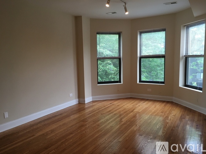 A room with wooden flooring and three windows.