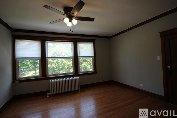 A room with a ceiling fan and a window with a view of trees.