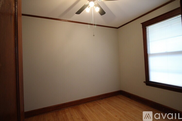 A room with a window and a fan on the ceiling.