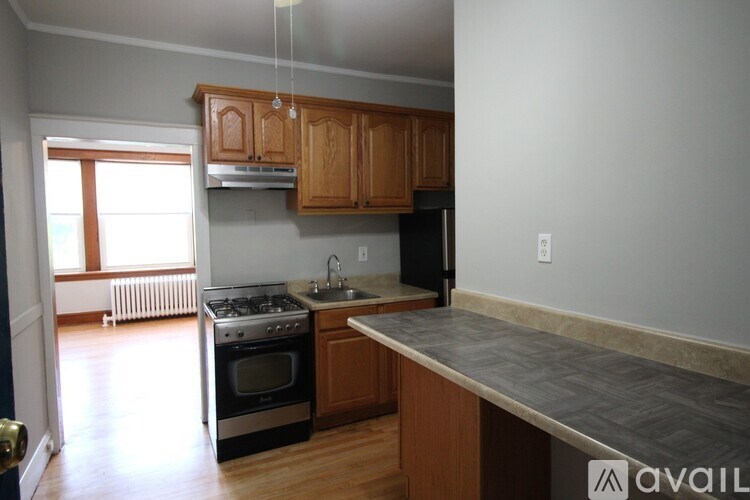 A kitchen with wooden cabinets and a black refrigerator.