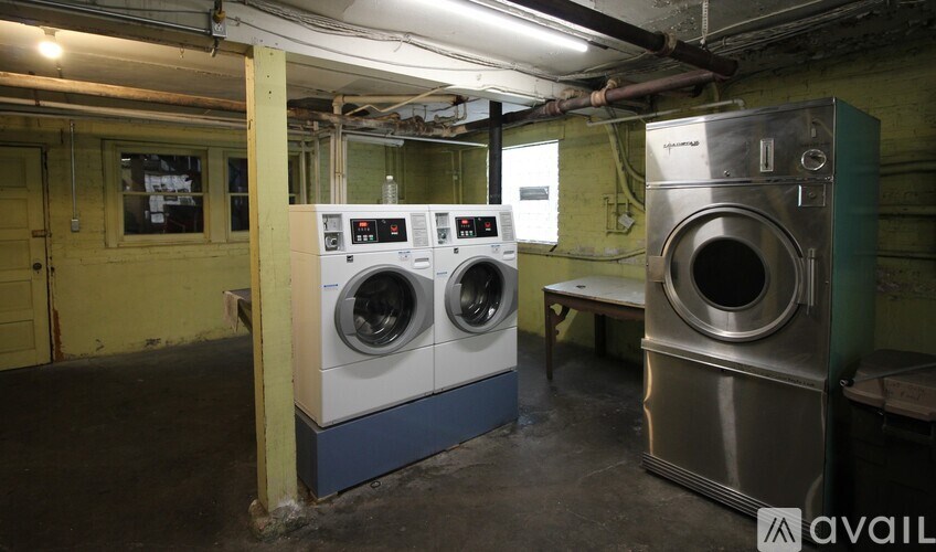 A large industrial washing machine sits in a room with other washing machines.
