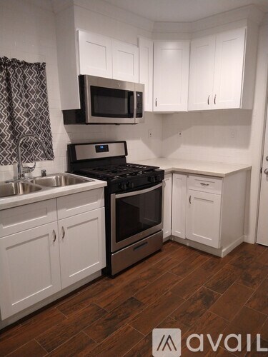A kitchen with white cabinets and a wooden floor.