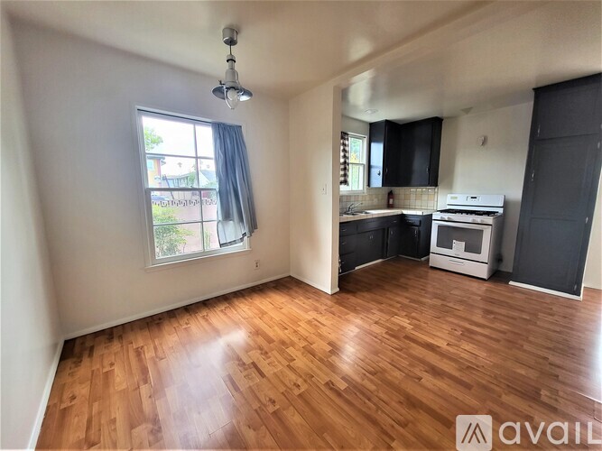 A room with wooden flooring and a window with a view of a garden.