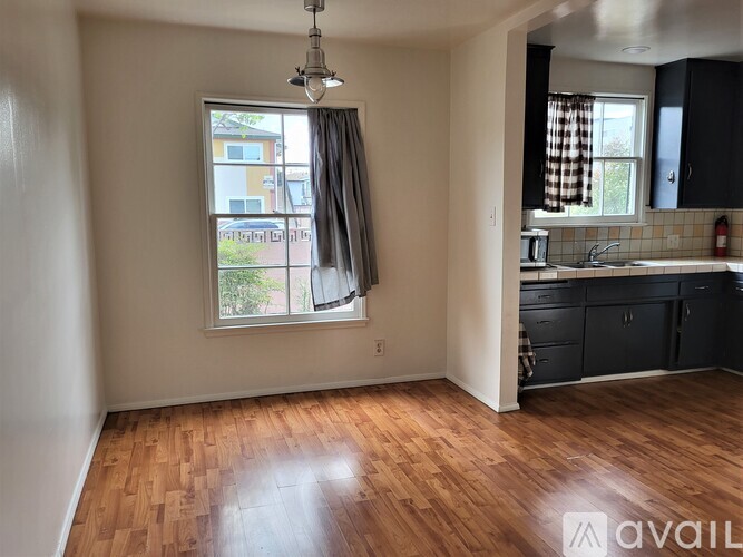 A room with wooden floors and a window with curtains.