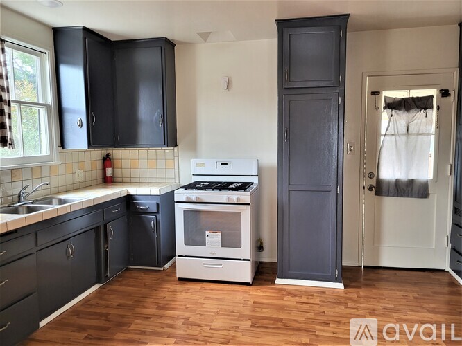 A kitchen with black cabinets and a white stove top oven.