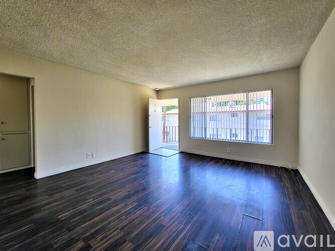 A room with wooden flooring and a window with blinds.