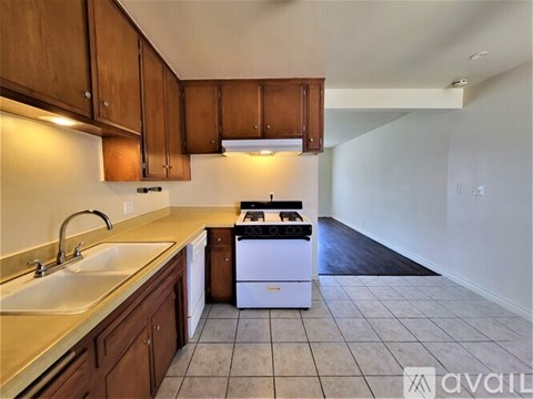 A kitchen with brown cabinets and a white dishwasher.