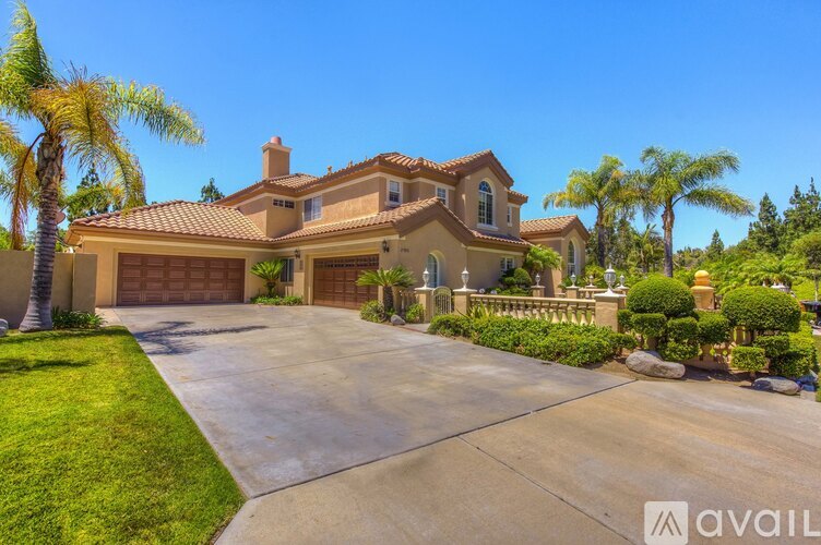 A large house with a driveway and palm trees in front.