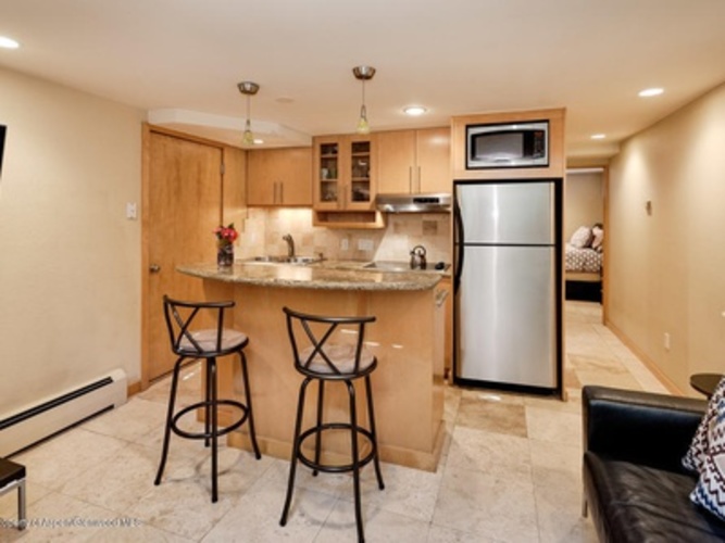 A kitchen with a bar stool and a refrigerator.