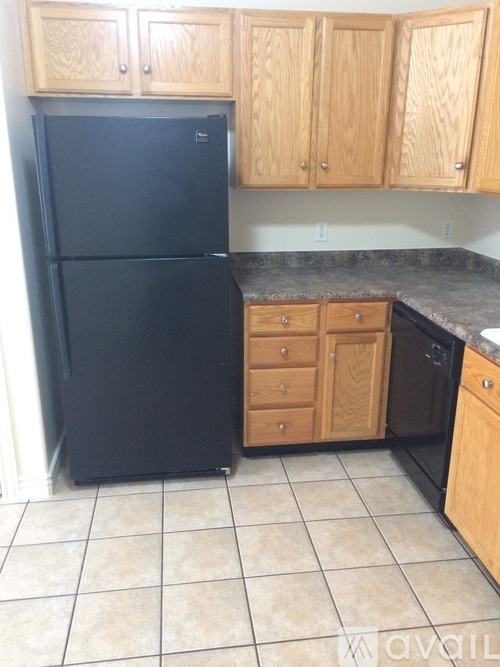 A black fridge in a kitchen with wooden cabinets.
