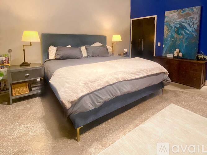 A bedroom with a large bed and a nightstand with a lamp.