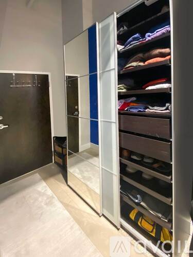 A walk-in closet with a mirror and shelves filled with clothes.