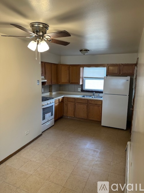 A kitchen with a white refrigerator and wooden cabinets.