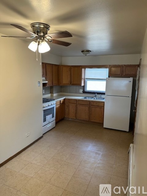 A kitchen with a white refrigerator and wooden cabinets.