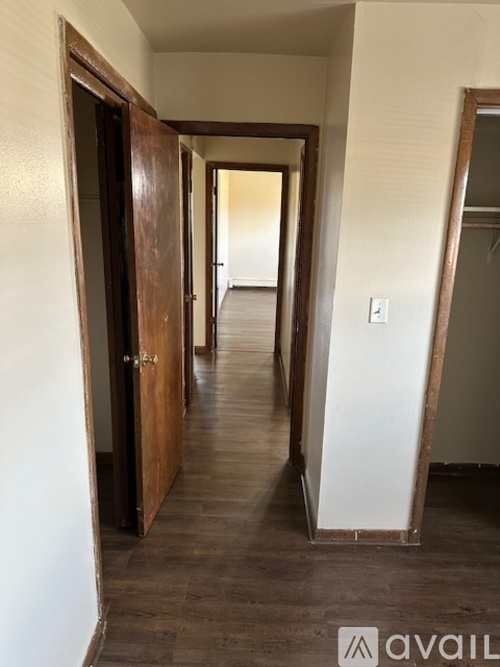 A hallway with a wooden door on the left and a white door on the right.