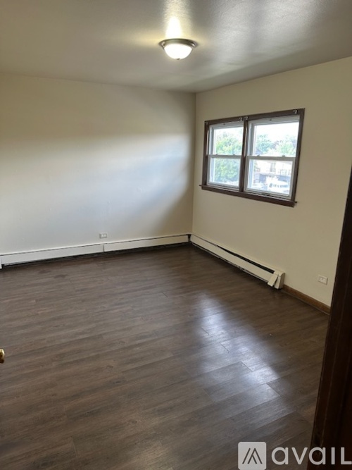 A room with wooden flooring and a window.