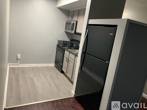 A kitchen with a black fridge and stove top oven.
