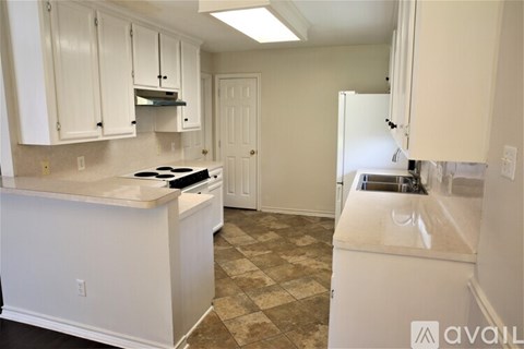 A kitchen with white cabinets and a tiled floor.