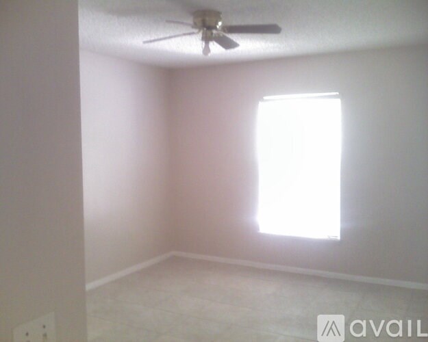 A room with a ceiling fan and a window letting in light.