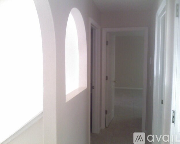 A hallway with a door on the right and a window on the left.