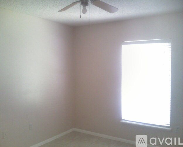 A room with a ceiling fan and a window letting in sunlight.