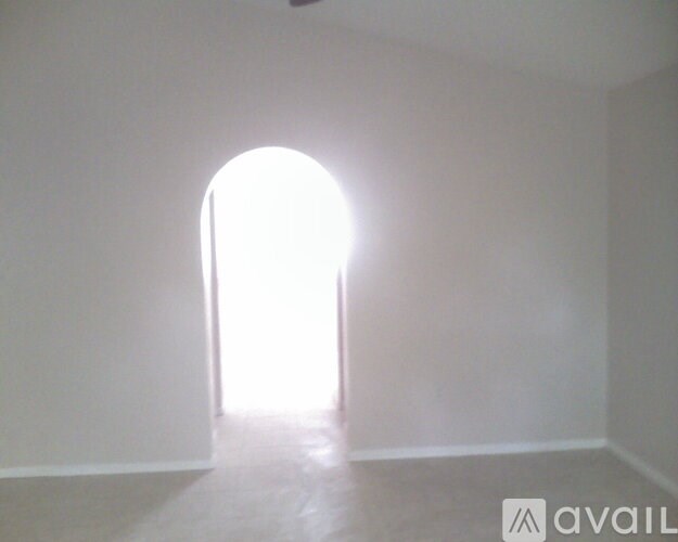 A room with a white wall and a white arched doorway.