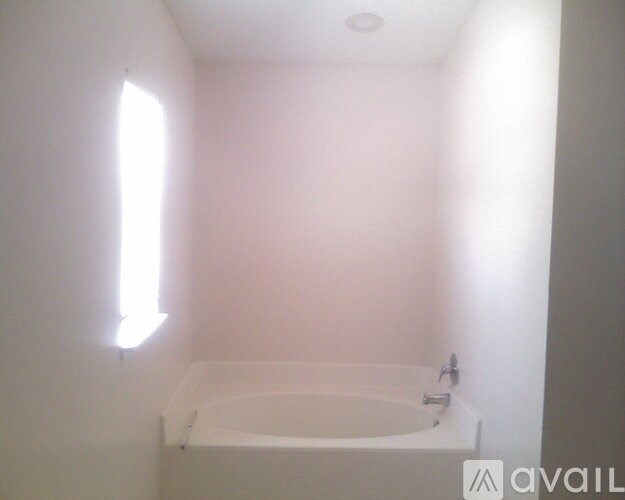 A white bathroom with a tub and a window.