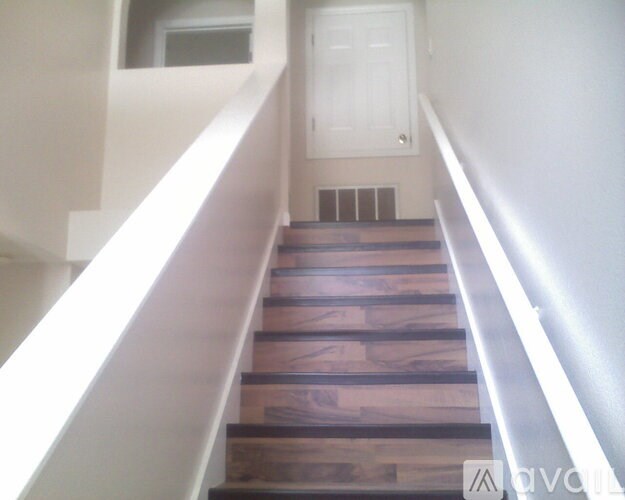 A set of stairs with wooden steps and a white handrail.