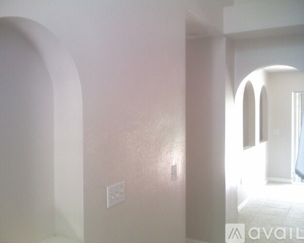 A white wall with a light switch and a window.