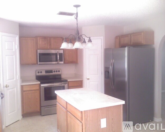 A kitchen with a refrigerator, oven, and microwave.