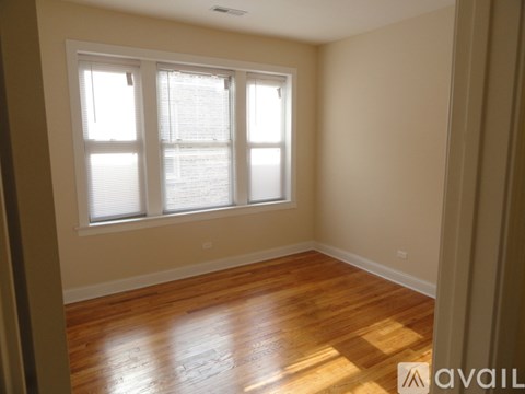 A room with wooden floors and a window with blinds.