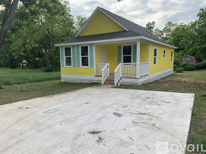 A yellow house with a porch and a green door.
