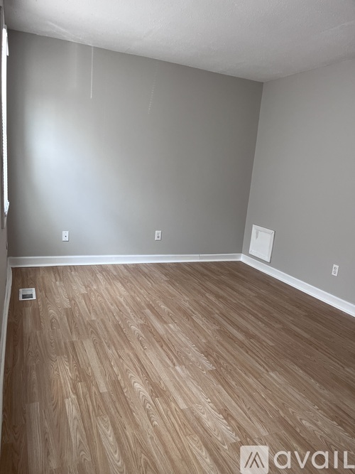 A room with a black fridge and a television on the wall.