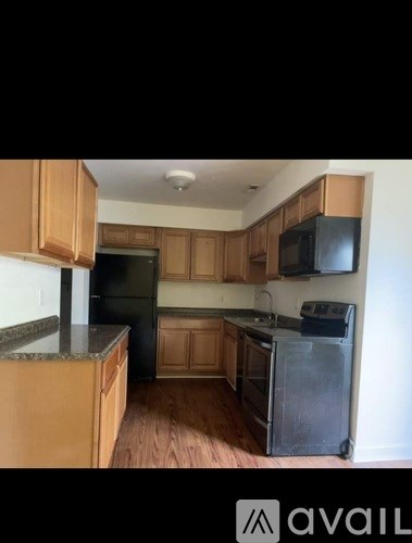 A kitchen with wooden cabinets and a black fridge.