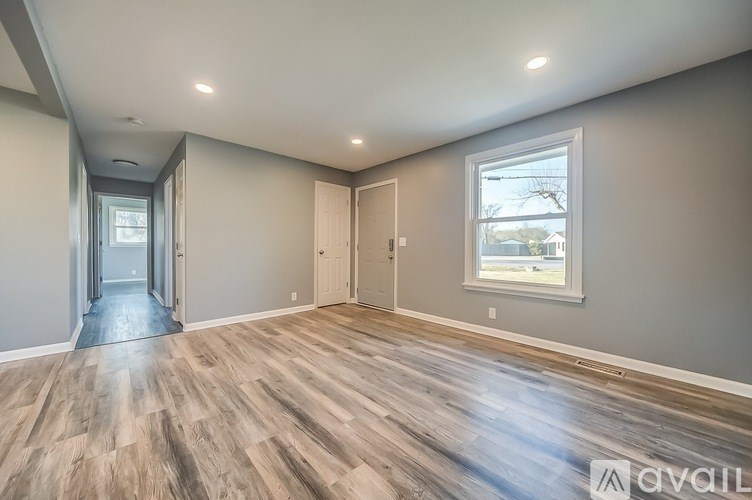 A spacious room with wooden flooring and a window.