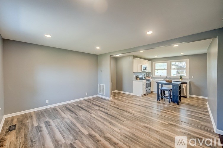 A spacious room with wood flooring and a desk with a chair.