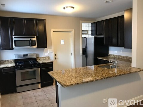 A kitchen with black cabinets and granite countertops.