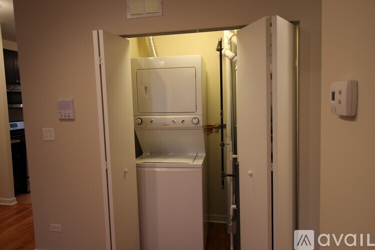 A white refrigerator is in a narrow space between a wall and a cabinet.