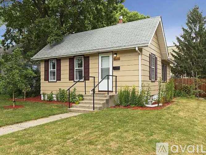 A small house with a front porch and a red flower bed.