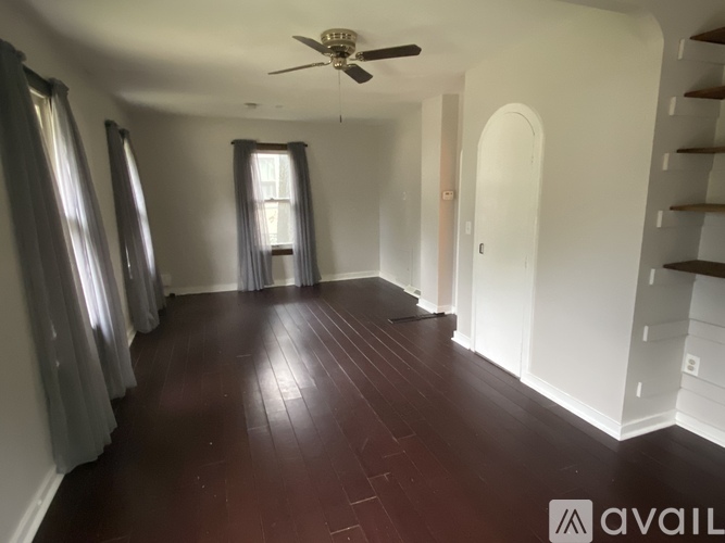 A room with a ceiling fan and wooden flooring.