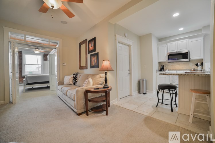 A living room with a couch, a table, and a fan.