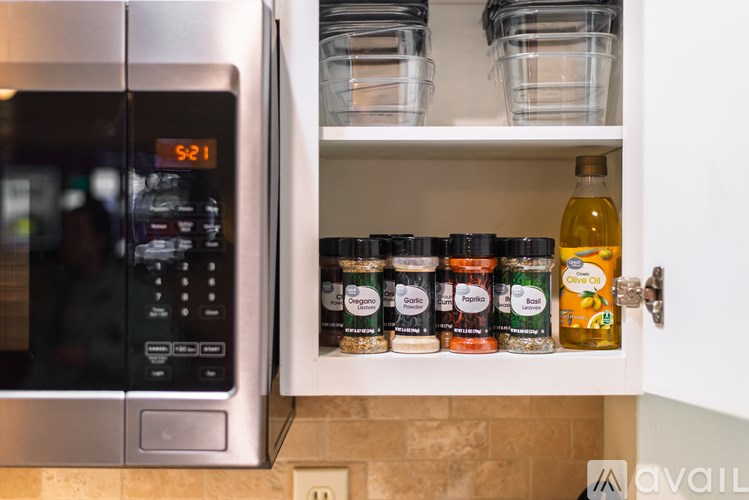 A kitchen with a microwave and an open pantry showing canned goods.