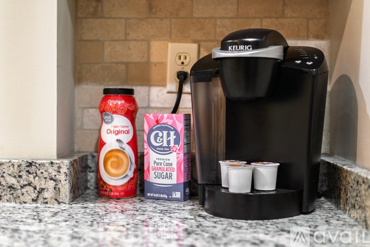 A Keurig coffee maker sits on a counter with a can of Orangeade and a carton of CH condensed milk.